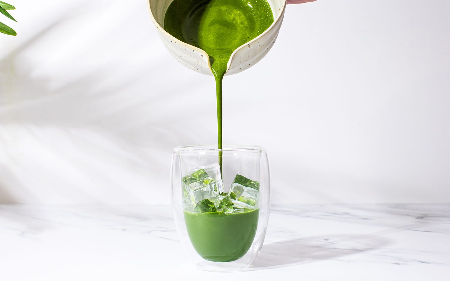 matcha being poured into a glass of ice