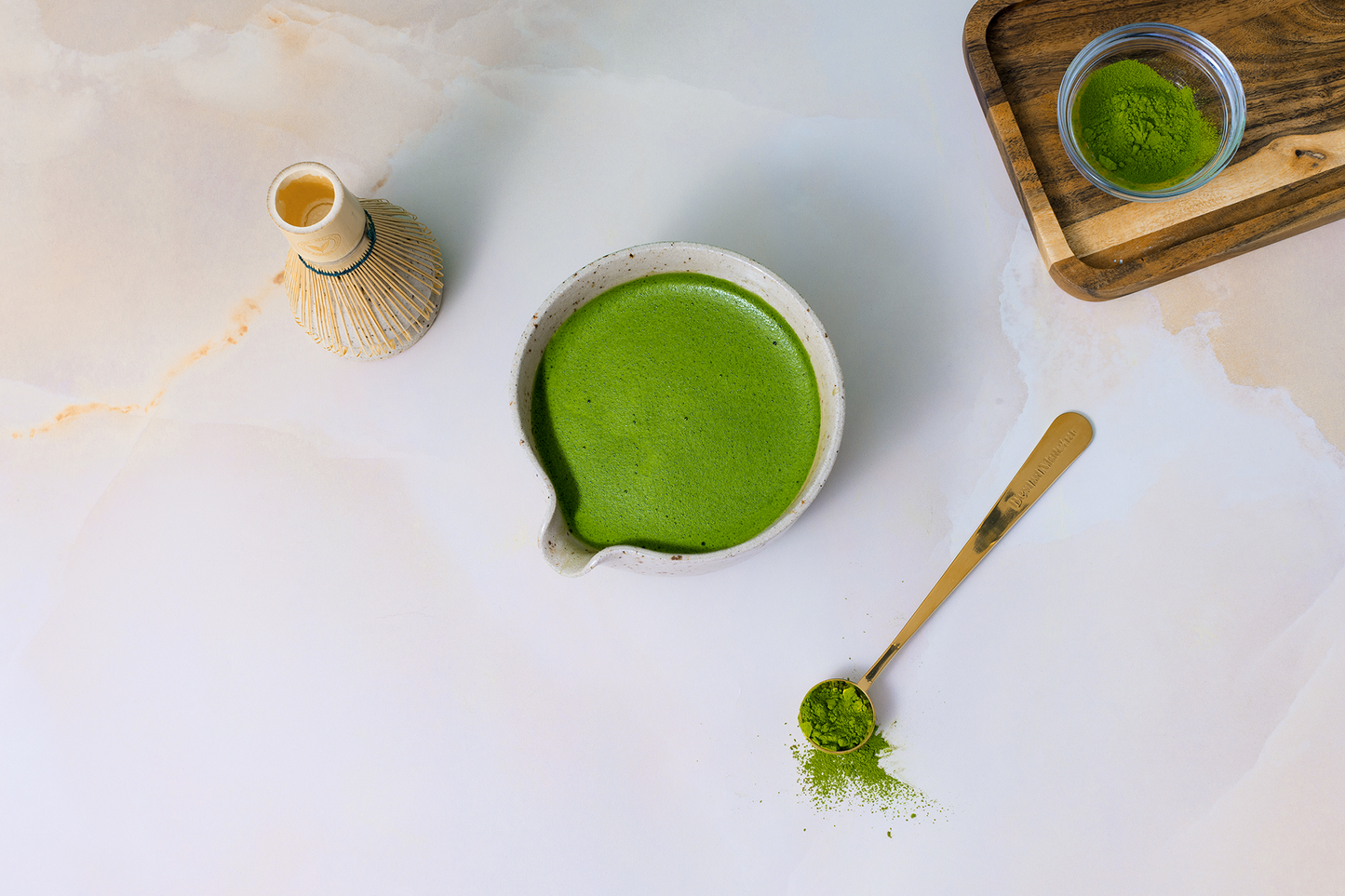Matcha green tea preparation with a bowl, whisk, and spoon on a light background
